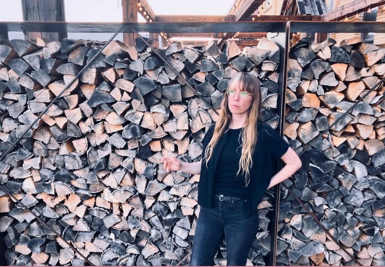 Kelley Smith in front of a pile of firewood